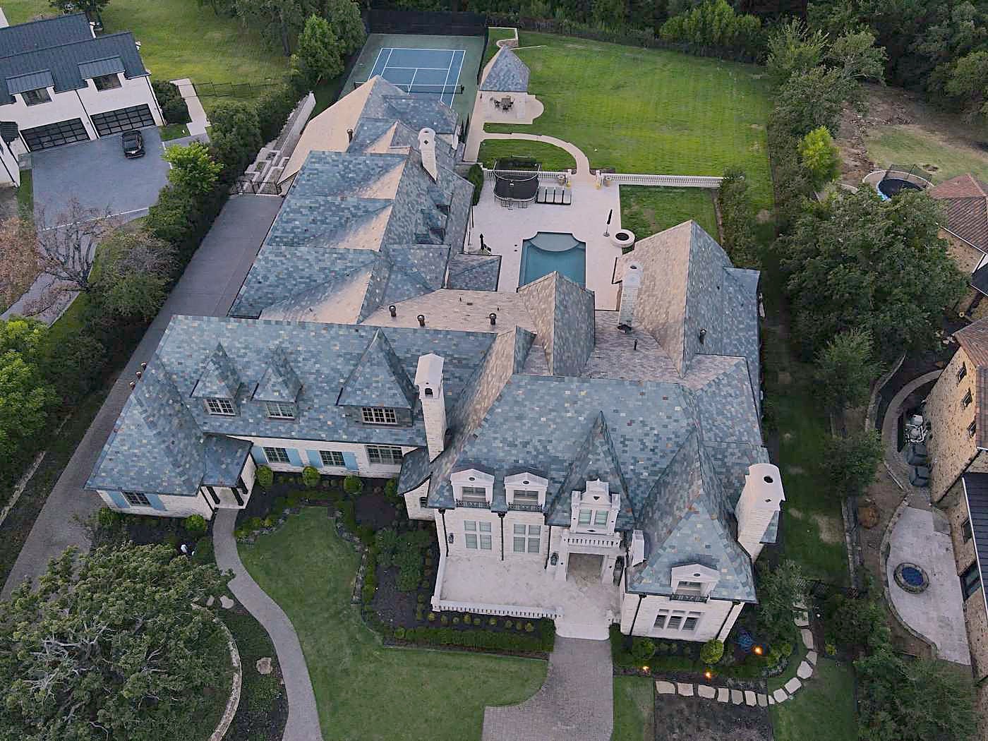 A large estate with a blue-grey roof and a pool, seen from the air