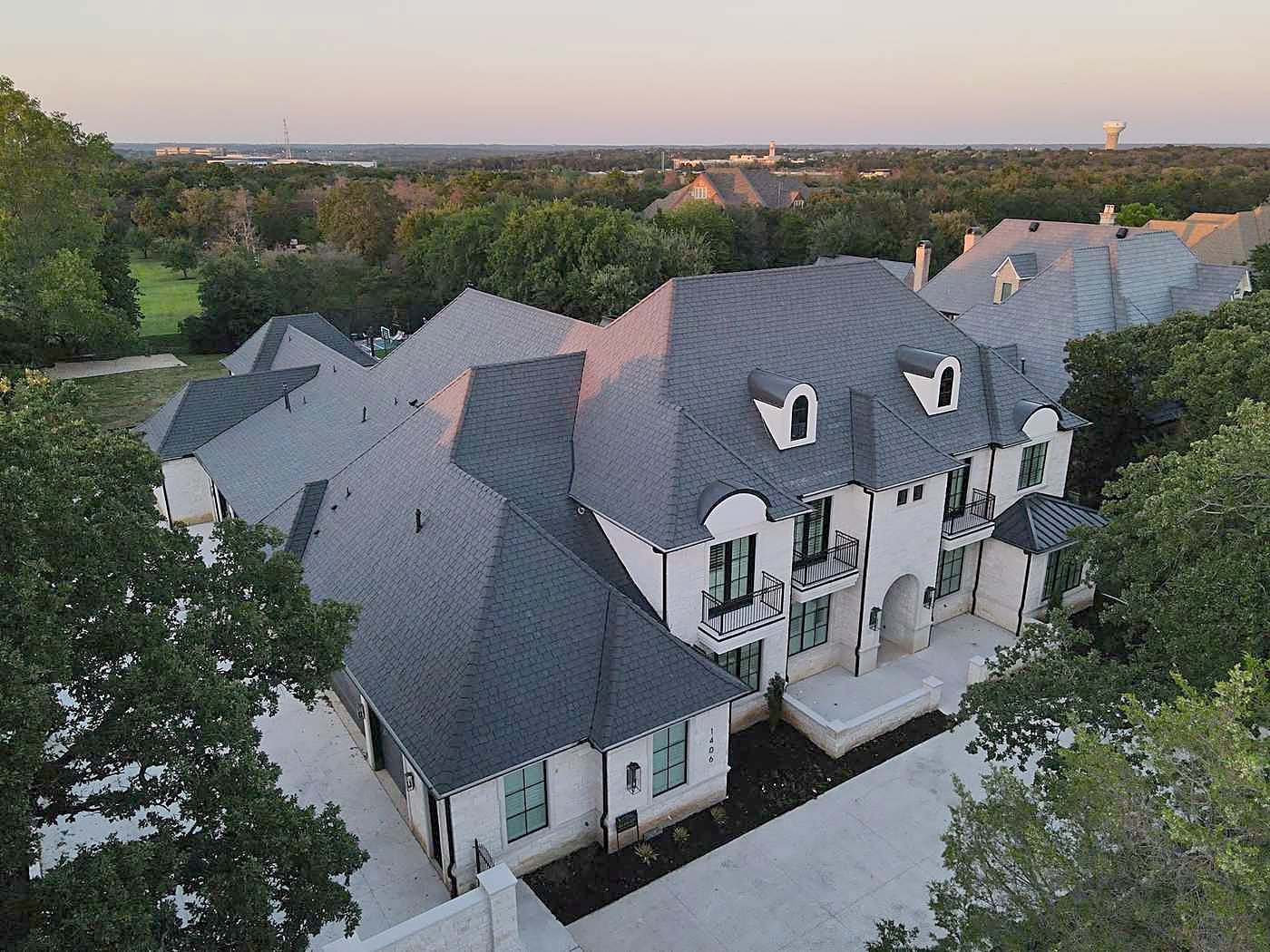 A new dark shingle roof on a two-story house at dusk, from the air